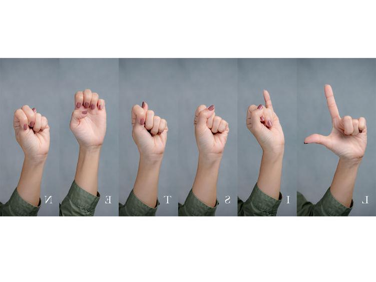 Hands gesturing using sign language to spell the word “listen”.